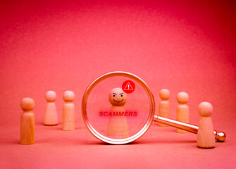 Hacker criminal, cyberattack, cybercrime, data system hacking and fraud and security attack concepts. Scammer, text and wooden figure with warning icons in magnifying glass lens on red background.
