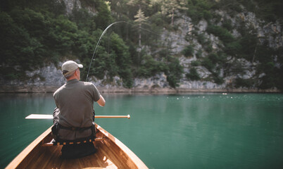 Man fishing from canoe on the lake, copy space