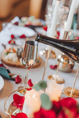 A man pours champagne into a golden glass at a festive romantic dinner in honor of an engagement in restaurant, closeup