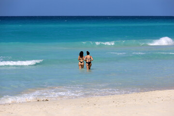 Two women in bikini swimming in azure sea water. Leisure together, beach vacation