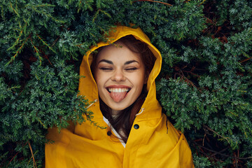 Serene Woman Enjoying Nature's Beauty Tongue Out in Yellow Raincoat in the Enchanted Forest
