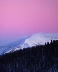 Pink winter sunset over the snowy mountain peaks. 