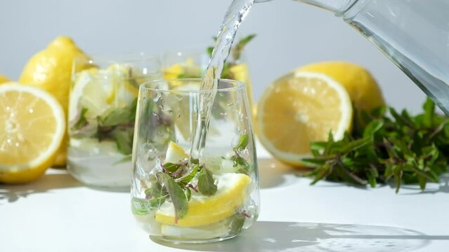 Lemon water with mint poured into glass, slow motion.
