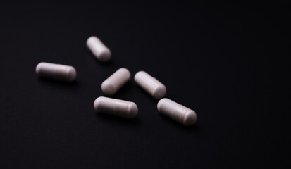 Creatine capsules on dark paper background. Soft focus. Copy space.