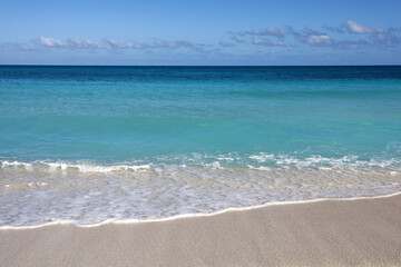 Empty sea beach with white sand, view to azure waves and blue sky with cloud. Caribbean coast, background for holidays on a paradise nature