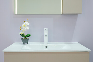 A white sink with a flower in a vase on top of it