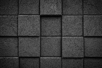 A black and white photo of a wall made of gray blocks. The blocks are arranged in a grid pattern,...
