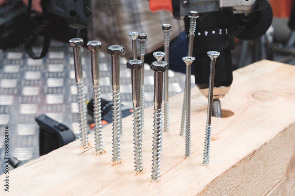 Poster a pile of screws are on a wooden surface. the screws are of different sizes and shapes. concept of o