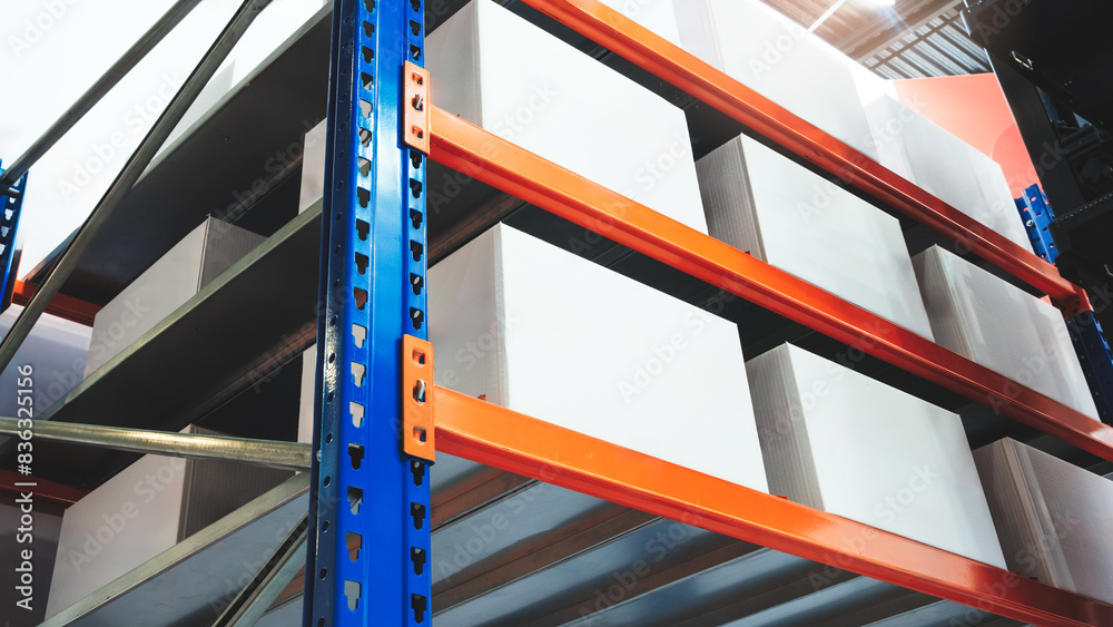Poster A stack of white boxes in warehouse on a blue and orange rack. The boxes are stacked on top of each other and are all the same size