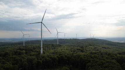 An Aerial view of a wind farm between the forest on a overcast day