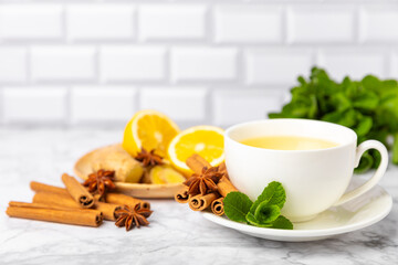 Fragrant hot tea with cinnamon stick and anise on a textured wooden background. A cup of hot tea with honey, lemon, mint and apples. Spicy tea with spices. Immunity tea. Health concept.Copy space.