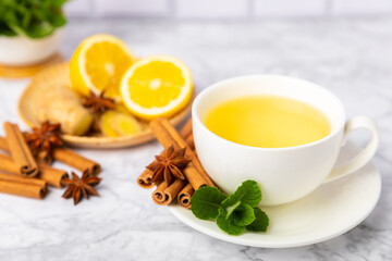 Fragrant hot tea with cinnamon stick and anise on a textured wooden background. A cup of hot tea with honey, lemon, mint and apples. Spicy tea with spices. Immunity tea. Health concept.Copy space.