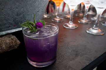 Trago con alcohol y frutas preparado en barra, primer plano, vaso de vidrio y flor como adorno