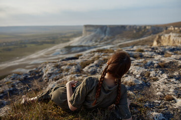 Woman sitting on cliff's edge admiring majestic valley view in nature travel concept