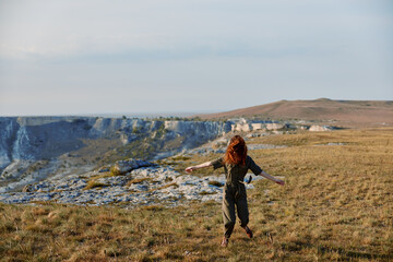 Woman with red hair standing on hill with outstretched arms embracing nature and freedom beauty and...