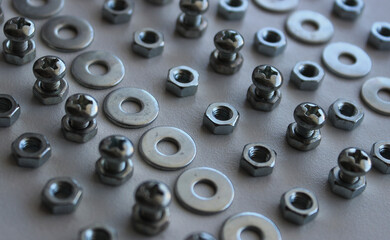 Shiny iron washers, spacers, nuts and bolts arranged in lines on the white plastic sheet. Stock Photo For Fastener Hardware Backgrounds
