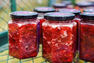 Fresh strawberry jam, preserved in jars, stands in a mesh metal box. Farm natural products. Conservation and preparations.