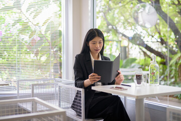 Professional businesswoman working on her smartphone in a bright, modern cafe with coffee and greenery