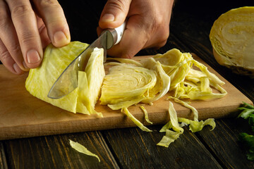 Cutting ripe cabbage for a vegetable dish. Close-up of a knife in a chef hand while cutting cabbage...