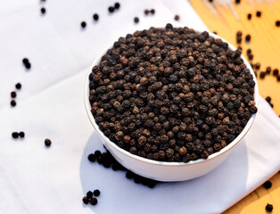 bowls filled with black peppers (Piper nigrum). Native to Malabar coast of India, it is widely used in culinary as spice and seasoning around the world.