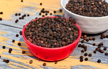 bowls filled with black peppers (Piper nigrum). Native to Malabar coast of India, it is widely used in culinary as spice and seasoning around the world.