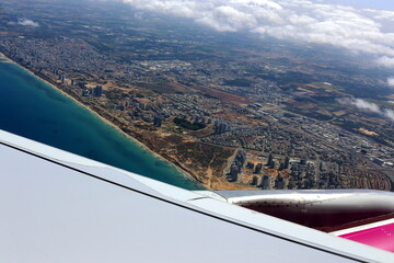 The wing of a jet plane and the scenery on the ground are visible through the porthole.