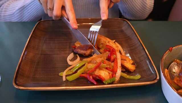 Traditional Georgian recipe Ojakhuri with pork and potatoes close-up. Female Hands Cutting Meat With Fork And Knife Potatoes On Plate Horizontal Top View Ojakhuri. Georgian cuisine,