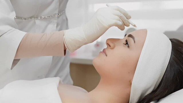 A woman is receiving a professional facial treatment with a needle, possibly a cosmetic procedure in a skincare clinic or medspa, focusing on beauty services in a hygienic environment