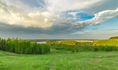 A panoramic view of rolling hills and a winding river, bathed in the warm light of a spring...