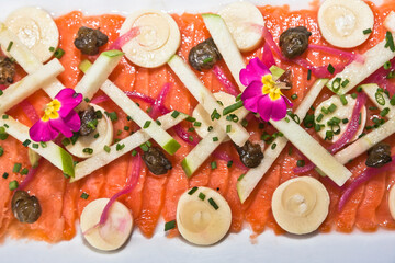 Salmon carpaccio with apple pieces, capers and edible flowers, gourmet food