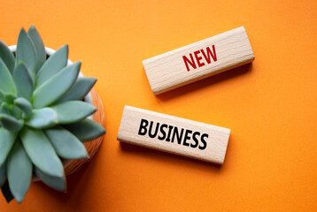 New business symbol. Concept words New business on wooden blocks. Beautiful orange background with...