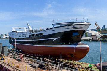 New building fishing vessel in dry dock on ship repairing yard.