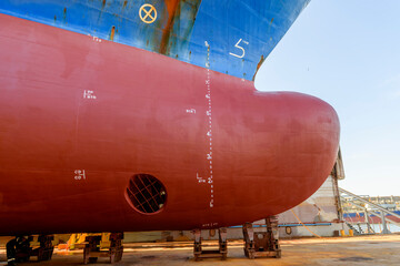 Cargo vessel in dry dock on ship repairing yard. Bow thruster.