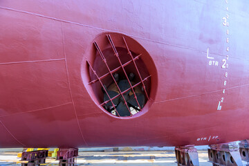 Cargo vessel in dry dock on ship repairing yard. Bow thruster.