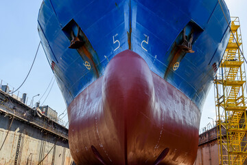 Cargo vessel in dry dock on ship repairing yard. Bulbous bow.