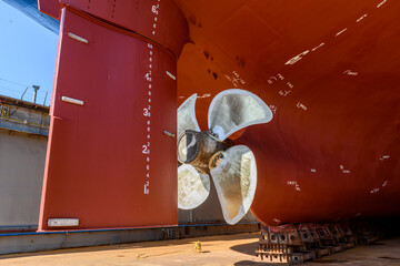 Cargo vessel in dry dock on ship repairing yard. Variable pitch propeller and rudder.