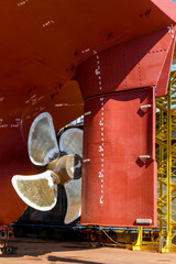 Cargo vessel in dry dock on ship repairing yard. Variable pitch propeller and rudder.
