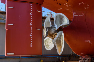 Cargo vessel in dry dock on ship repairing yard. Variable pitch propeller and rudder.