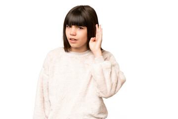 Little girl over isolated green chroma key background listening to something by putting hand on the ear