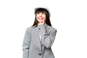 Little girl playing as a architect with helmet and holding blueprints over isolated background thinking an idea while looking up