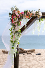 Wedding arch decorated with flowers on the beach