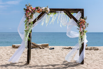 Wedding arch decorated with flowers on the beach