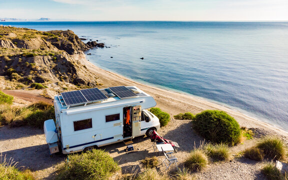 Caravan with solar panels on roof camp on sea, Spain. Aerial view.