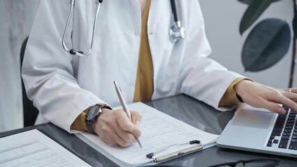 Doctor woman is working on laptop with medical reports. Healthcare professional reviews patient files and inputs data in a clinic setting. Medicine