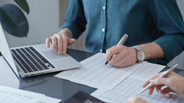 Business people professionals analyzing data on laptop. Close-up of auditor's hands reviewing financial spreadsheets in a modern office setting. Finance teamwork