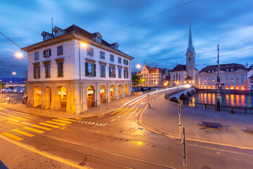 Fototapeta premium Panoramic evening view of Fraumunster and Munsterbrucke with illuminated streets in Zurich, Switzerland.