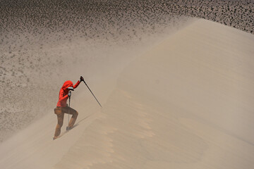 Woman Hiking Up A Sand Dune