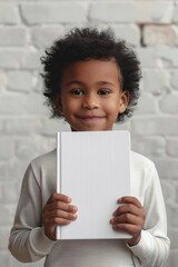 Young Child Holding a White Book in a Light Room