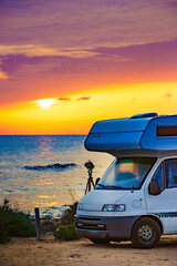 Camper and camera on tripod on beach at sunrise