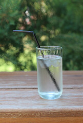 Cold water glass with straw on wooden table